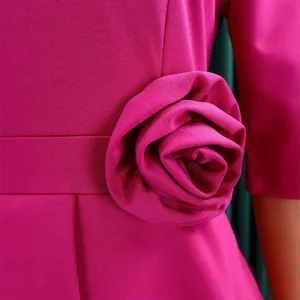 Detailaufnahme einer eleganten 3D-Stoffblume an einem magentafarbenen Partykleid