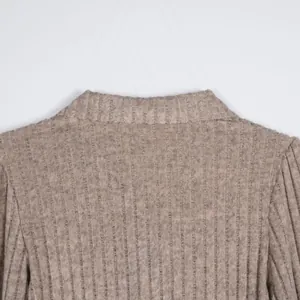 Close-up detail of the ribbed texture and collar design on a taupe knit sweater.