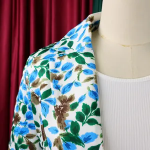 Dettaglio ravvicinato di un blazer bianco slim fit da donna con vivace stampa floreale blu