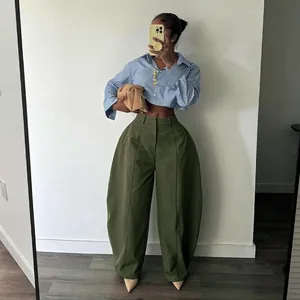 Close-up view of the olive green oversized wide-leg trousers styled with a striped shirt.