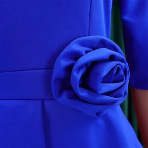 Nahaufnahme eines eleganten königsblauen Kleides mit großer 3D-Stoffblume an der Taille