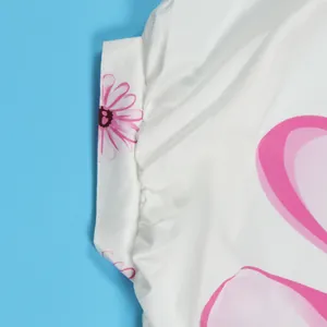 Close-up detail van een wit shirt met elegante roze bloemen- en hartpatroonprints.