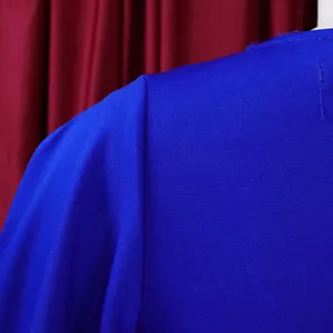 Macro view of royal blue dress fabric texture and shoulder stitching for office commuter wear.