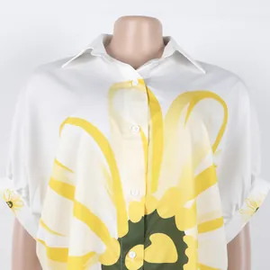 Elegante witte blouse met grote gele bloemenprint en een klassieke reverskraag met knoopjes