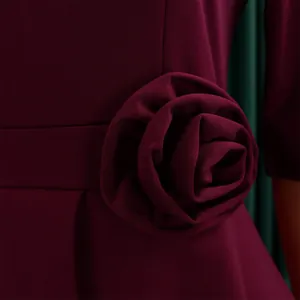 Detailaufnahme der dreidimensionalen Stoffblume an einem eleganten burgunder Kleid