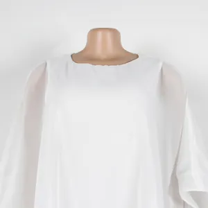 Primer plano de un vestido de gasa blanca suelto estilo poncho con escote redondo