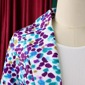 Dettaglio ravvicinato del rever di un blazer con stampa astratta nei toni viola e blu
