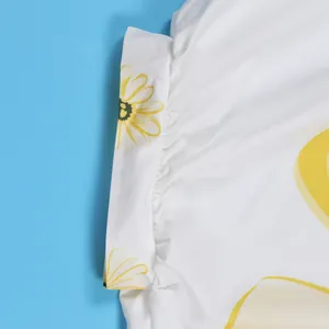 Detail van de elegante gele bloemenprint op witte stof met details van geplooide naden.