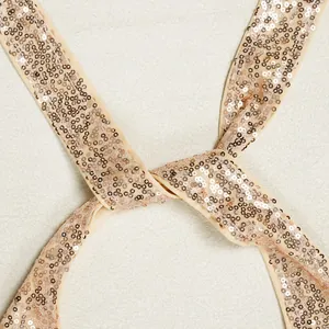 Makrodetail eines eleganten champagnerfarbenen Paillettenbands an einem Abendkleid.