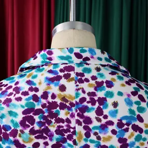 Vista dettagliata di un blazer con motivo floreale viola e ottanio su un manichino.