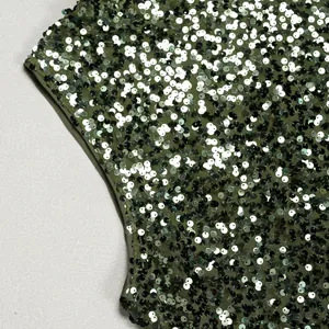 Close-up macro detail of shiny dark green sequins and mesh fabric on an elegant evening dress