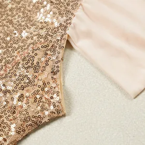 Nahaufnahme von schimmernden roségoldenen Pailletten und nudefarbenem Netzstoff an einem Kleid.