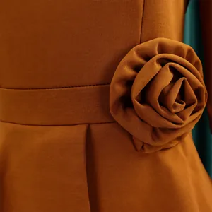 Detailansicht eines eleganten braunen Kleides mit handgefertigtem 3D-Stoffblumenakzent und Rippstoff