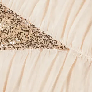 Nahaufnahme mit aufwendigen Goldpailletten und plissiertem Netzstoff an einem Kleid