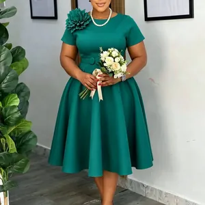 Detail van een elegante donkergroene jurk met een decoratieve bloem op de schouder.