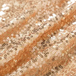 Detailansicht glitzernder roségoldener Pailletten auf elegantem Abendkleid aus Netzstoff