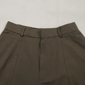 High-detail close-up of the elasticated waistband and fabric texture on casual brown trousers.