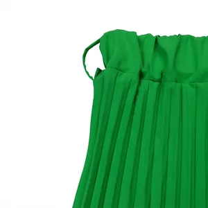 Détail en gros plan d'une jupe midi plissée vert vif soulignant la taille haute