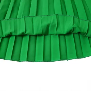 Détail en gros plan de l'ourlet d'une jupe plissée vert vif avec texture de tissu