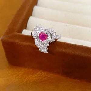 Macro view of a luxury silver flower-shaped ring featuring a brilliant red gemstone center.