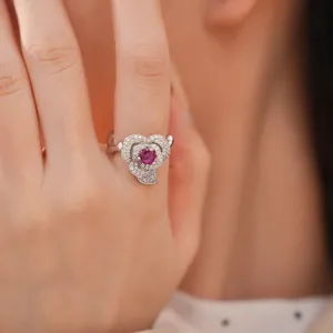 Close-up of a luxury flower-shaped ring with red zircon on an Asian model finger.