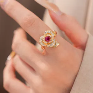 Close-up detail of a luxury 14k gold plated flower open ring with red zircon stone