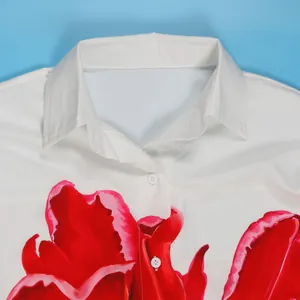 Detail van witte blouse met rode bloemenprint en een elegante omgeslagen kraag.