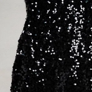 Macro close-up detail of shimmering black sequins on elegant mesh cocktail dress fabric