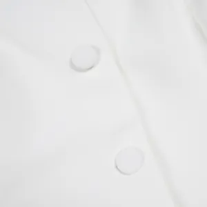 Détail macro montrant des boutons recouverts de tissu blanc sur un combishort élégant.