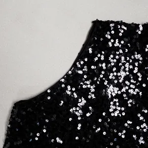 Close-up detail showing shimmering silver sequins on black mesh dress fabric texture