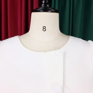 Detailed view of the elegant round neckline on a white two-piece dress with buttons.