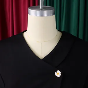 Close-up detail of a black textured top with a white daisy button on the V-neck lapel