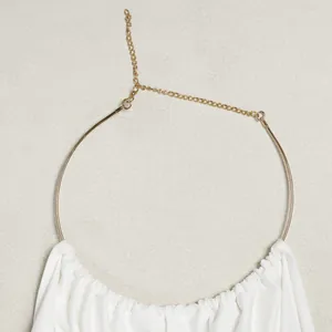 Detailed macro shot of elegant gold metal halter neck ring on white pleated top