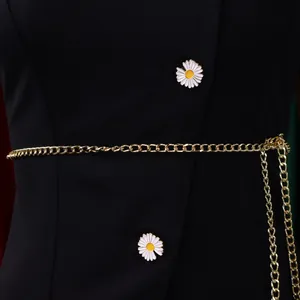 Close-up detail of black fashion top featuring daisy buttons and elegant gold chain belt