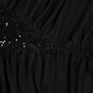 Detailansicht eines schwarzen Abendkleids mit Mesh-Patchwork und schimmernden Pailletten