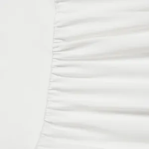 High-quality close-up detail of white pleated fabric showing elegant texture and seam