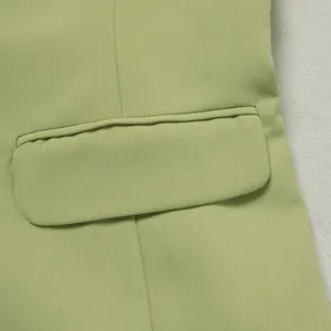 Gros plan du tissu vert clair et de la poche à rabat d'une combinaison ajustée.
