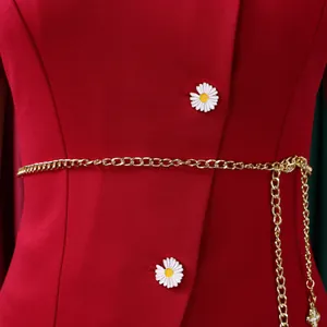 Close-up of red top featuring daisy buttons and a delicate gold chain belt detail.