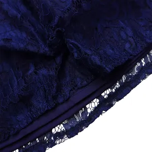 Macro detail showing the intricate navy blue floral lace fabric and hem of the dress