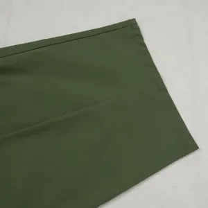 Close-up detail of the hem and seam on olive green loose-fit commute trousers