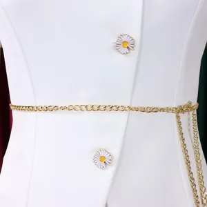 Detailed view of a white elegant blazer featuring daisy buttons and a gold chain belt.