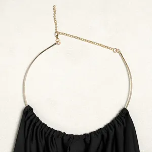 Close-up of the elegant golden neck ring and pleated black fabric on this halter top
