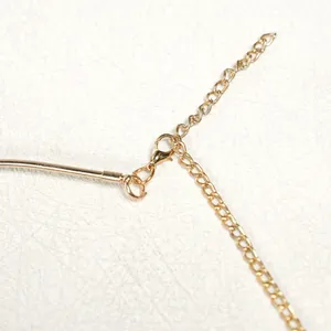 Close-up macro view of the gold metal lobster clasp and adjustable extension chain