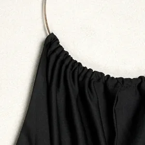 Detail of elegant black halter top with pleated fabric and gold ring hardware.
