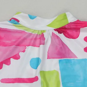 Close-up detail of colorful abstract geometric watercolor print on a dress neckline area.