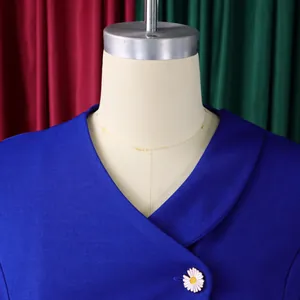 Close-up detail of a blue fashion top featuring an asymmetrical collar and daisy brooch