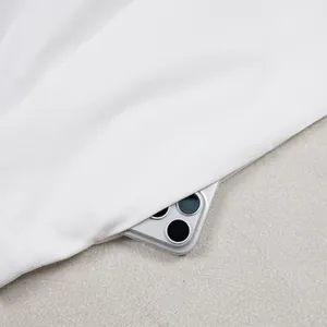 Detail view of deep side pocket on white loose-fit casual trousers with smartphone inside.