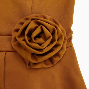 Exquisites Detail einer 3D-Stoffrose an der Taille eines eleganten orangefarbenen Sommerkleids