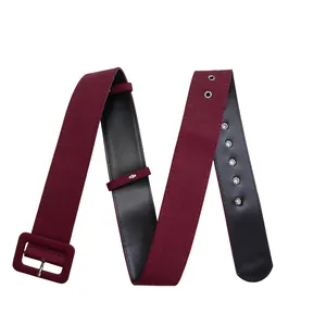 Close-up of a wide burgundy fabric belt featuring a square buckle and silver eyelets.