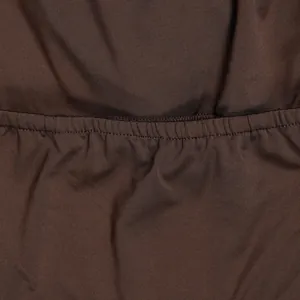 Close-up detail of the brown pleated fabric texture and elastic waistband stitching